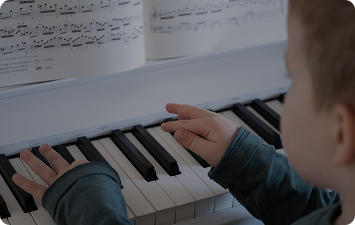 A child reads sheet music while playing the piano