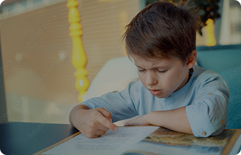 A child concentrates while reading a book on his desk